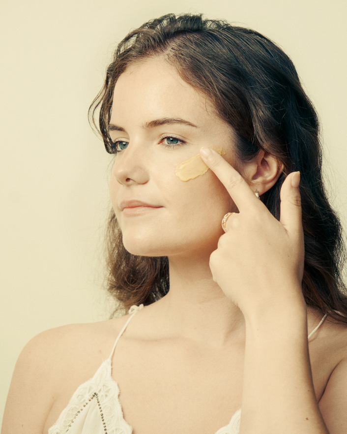 Woman applying DOMA Longevyouth Cream to her face and neck